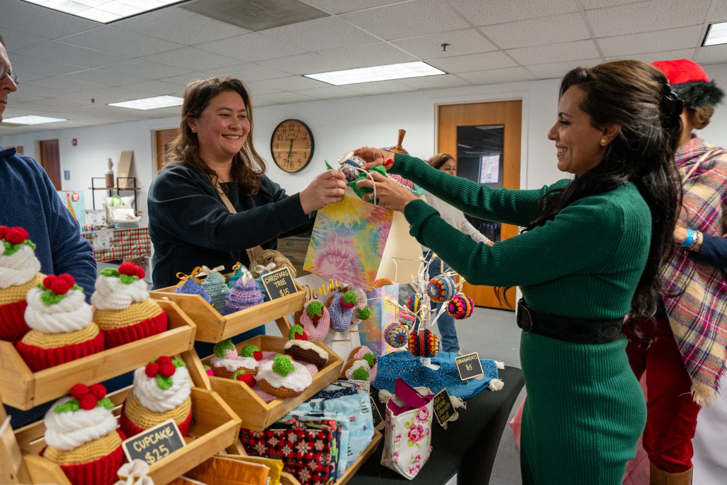 A shopper and a maker exchanging a handmade gift across a market table