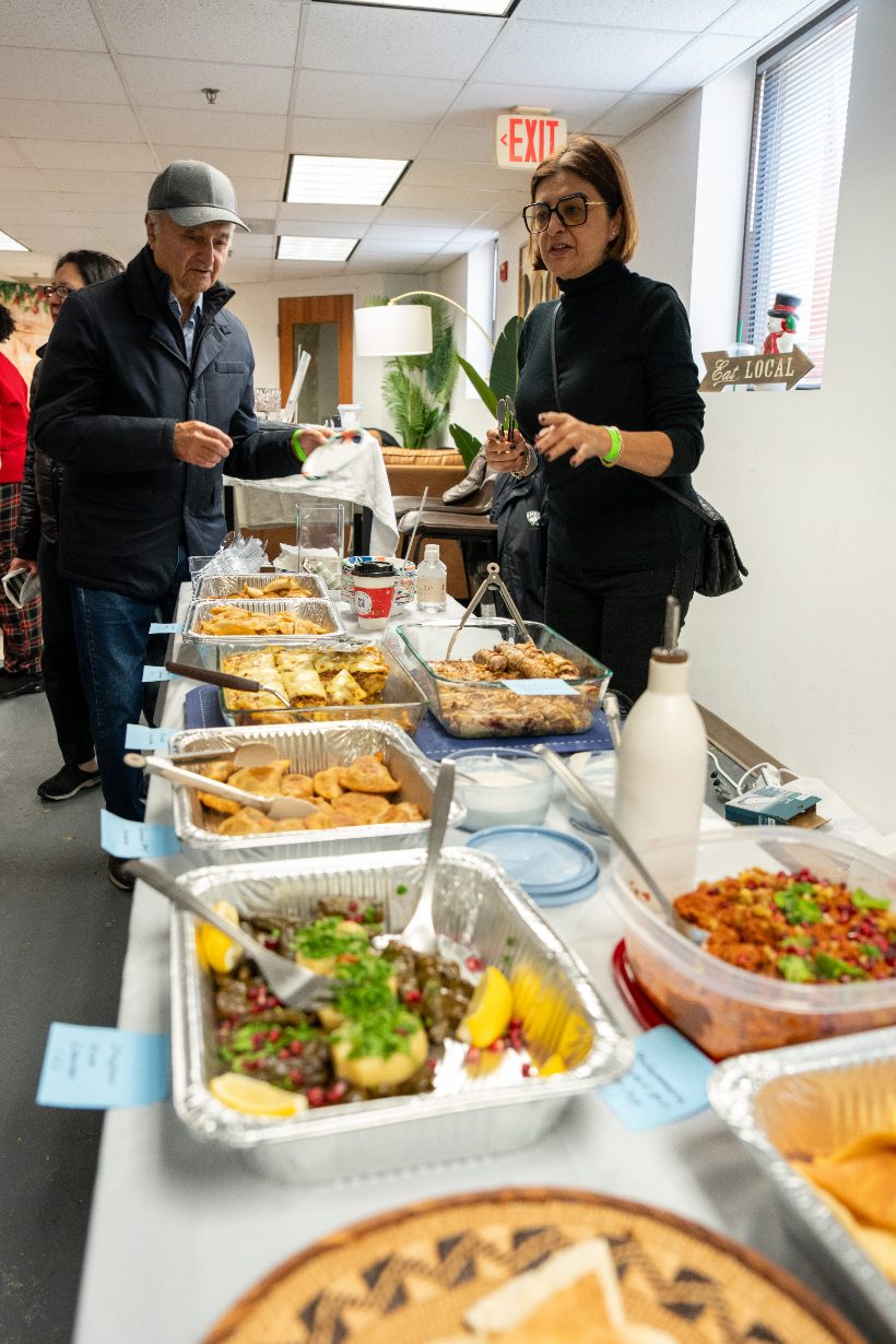 Two shoppers choosing from a long table of homemade dishes